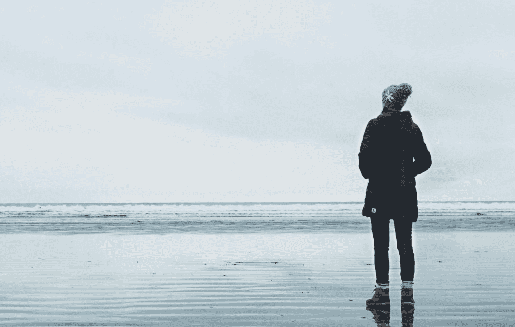 a person standing on a beach looking out at the ocean.