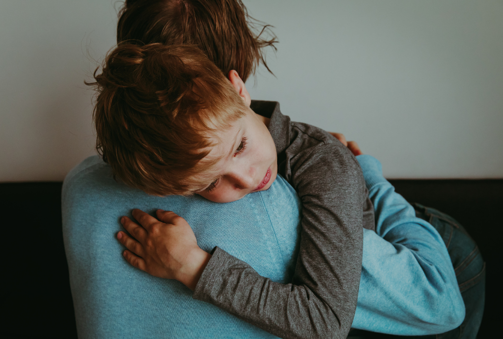 a little boy with PTSD hugging a woman on the back of a couch