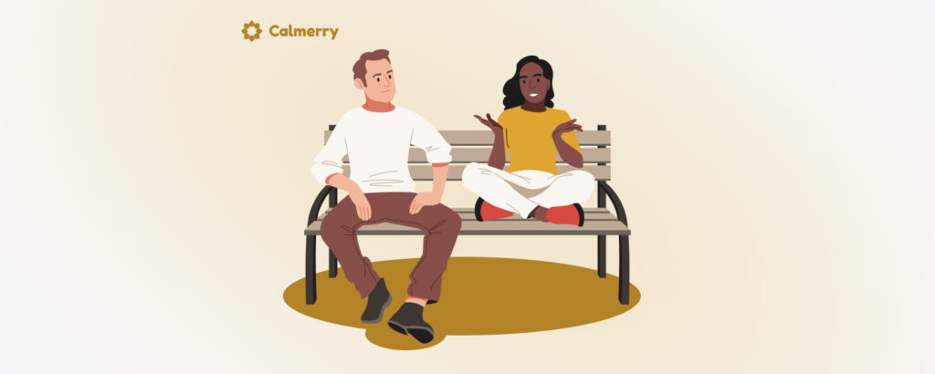 A man and a woman sitting on a park bench against a pale background. The man, on the left, wears a white shirt and brown pants, and is seated with one leg crossed over the other. The woman, on the right, wears a yellow top and white pants, and is animatedly talking with her hands gesturing and practicing assertive communication. The logo 'Calmerry' is displayed at the top left corner.